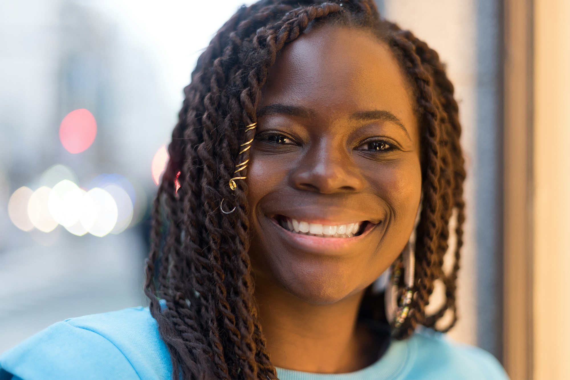 Pretty young black woman in the middle of the city, smiling at camera.