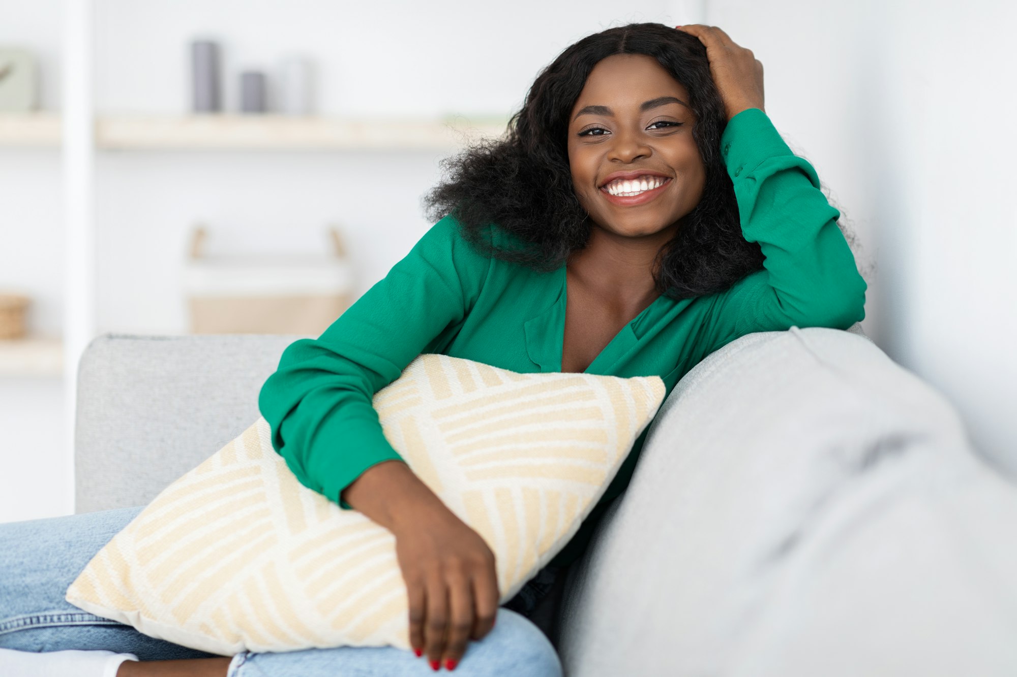 Smiling pretty african american woman sitting on couch at home